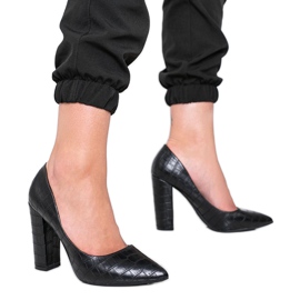 Svarta pumpar på en stolpe med ett ormskinnsmönster This Way