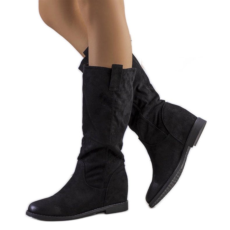 Svarta stövlar på Maes kilklack inomhus