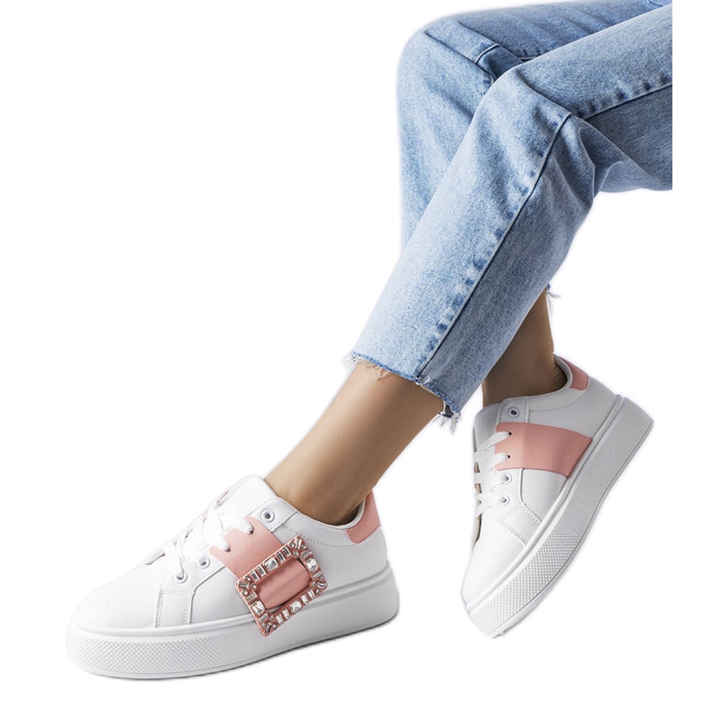 Vita sneakers dekorerade med ett rosa Ike-spänne