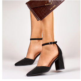 Svarta pumps på en stolpe fäst vid ankeln