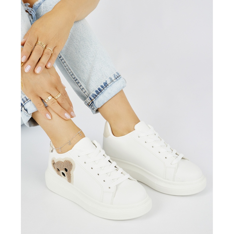 Vita damsportskor med en nallebjörn