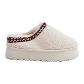 Ljusbeige tofflor av fårskinn på en plattform med päls