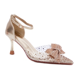 Kvinnors höga klackar dekorerade med en imponerande guldrosett gyllene