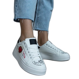 Vita sneakers dekorerade med en lapp och inskriptioner på plattformen