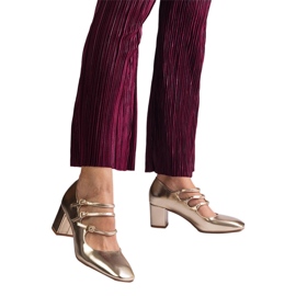 Gyllene pumpar på stolpen med dekorativa spännen