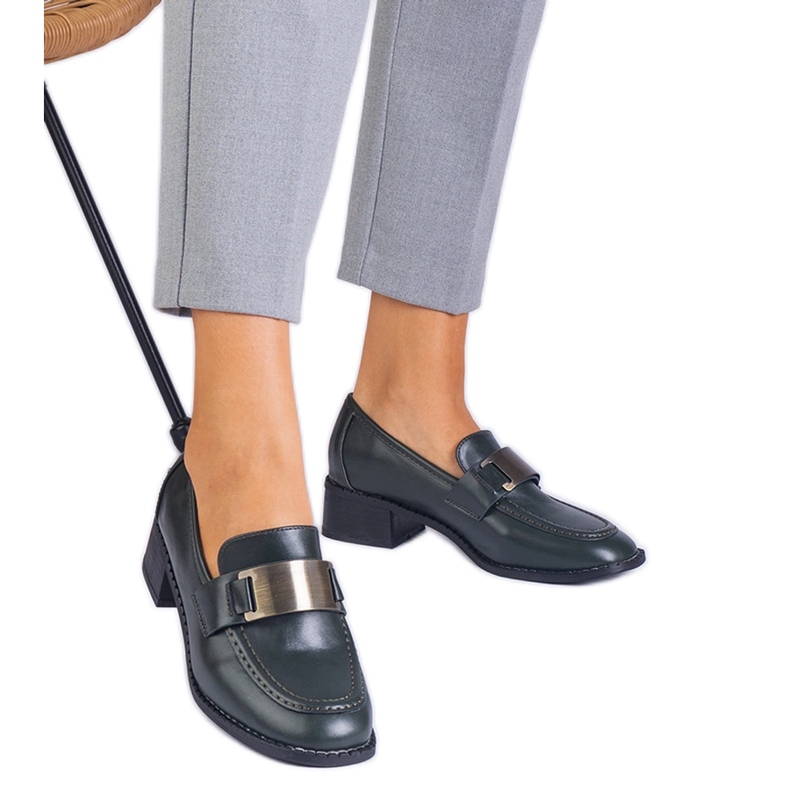 Gröna skor på en låg stolpe med en metallisk dekoration