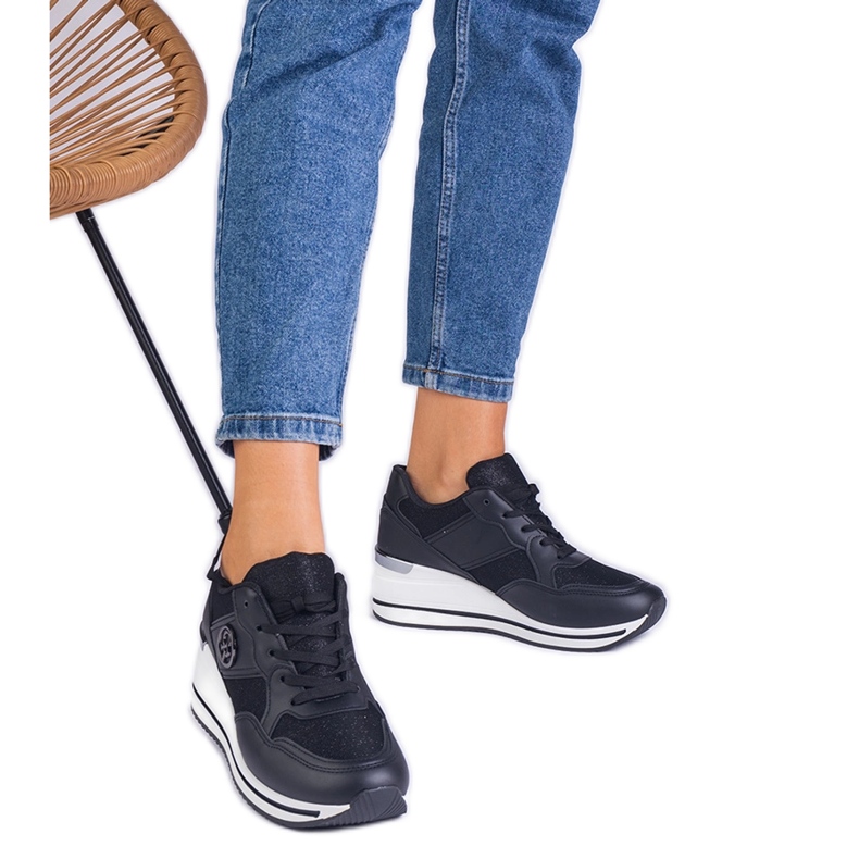 Svarta kvinnors sneakers dekorerade med en metallinsats