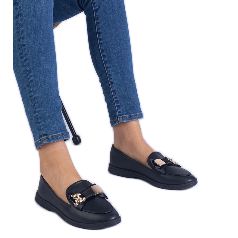 Svarta loafers dekorerade med en båge och en gyllene nallebjörn