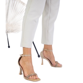 Gyllene eleganta sandaler på en hög häl dekorerade med zirkoner