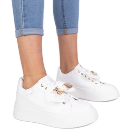 Vita sneakers dekorerade med en båge och en gyllene nallebjörn