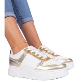 Gyllene kvinnors sneakers på en tjock sula dekorerad med glitter