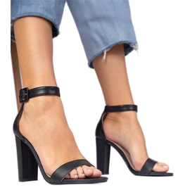 Svarta sandaler på stolpen fästes på vristen