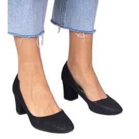 Svarta kvinnors pumpar med en materiell finish