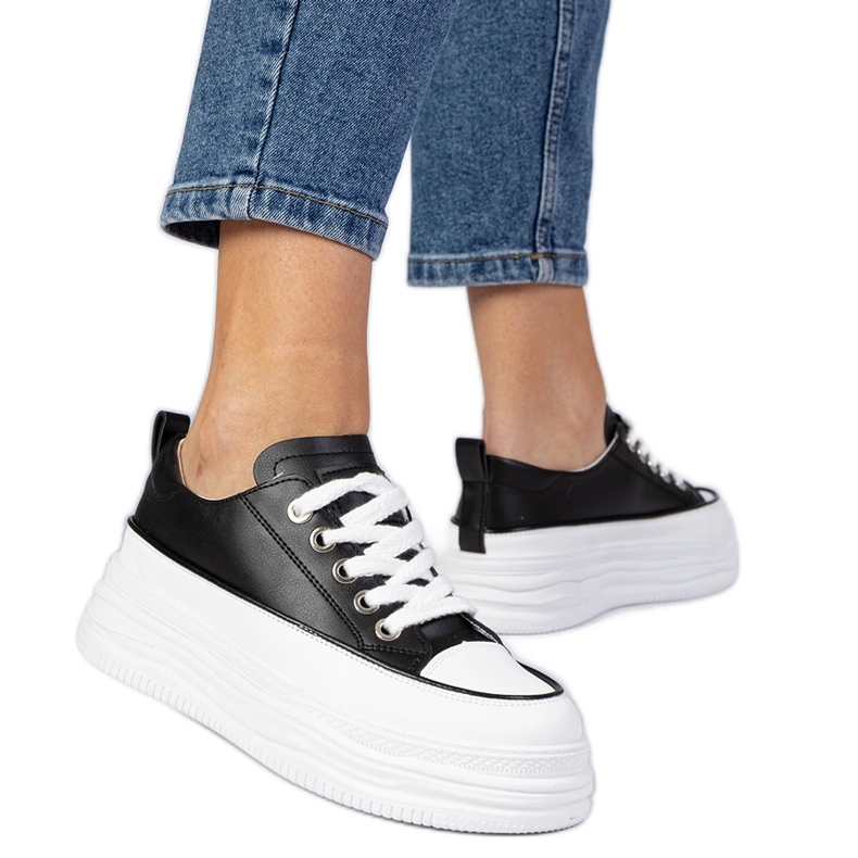 Svartvita kvinnors sneakers på en hög sula