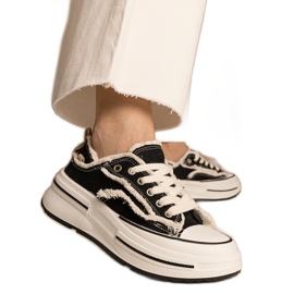 Svarta kvinnors sneakers på en hög sula