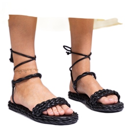 Svarta kvinnors sandaler flätade