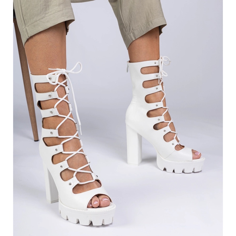 Vita stövlar på en hög pelare med utskärningar