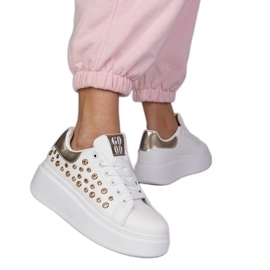 Vita sneakers med en gyllene insats och tappar