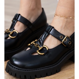 Svarta skor på en tjock sula med en gyllene dekoration