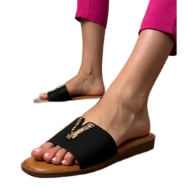Svarta flip flops med en gyllene dekoration