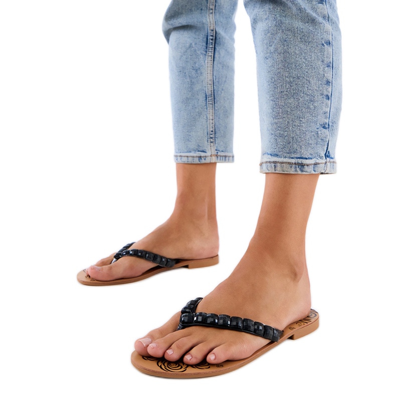 Svart flip -flops flip -flops dekorerade med stenar