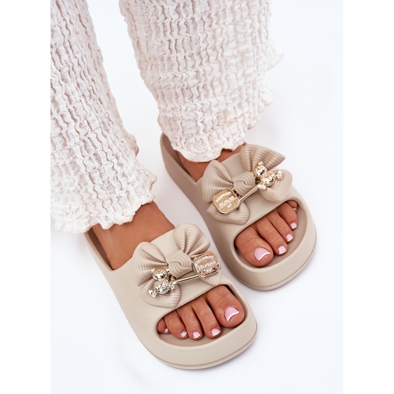 Kvinnors skum flip flops på plattformen med en båge och en mörk beige brosch