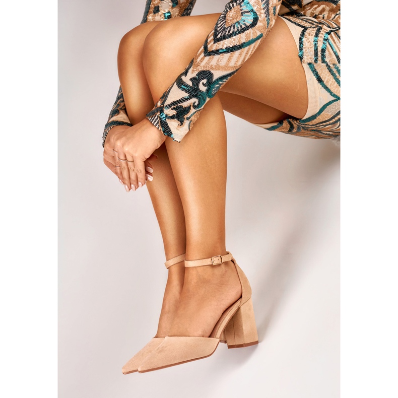 Beige pumps på en stolpe fäst vid ankeln 1