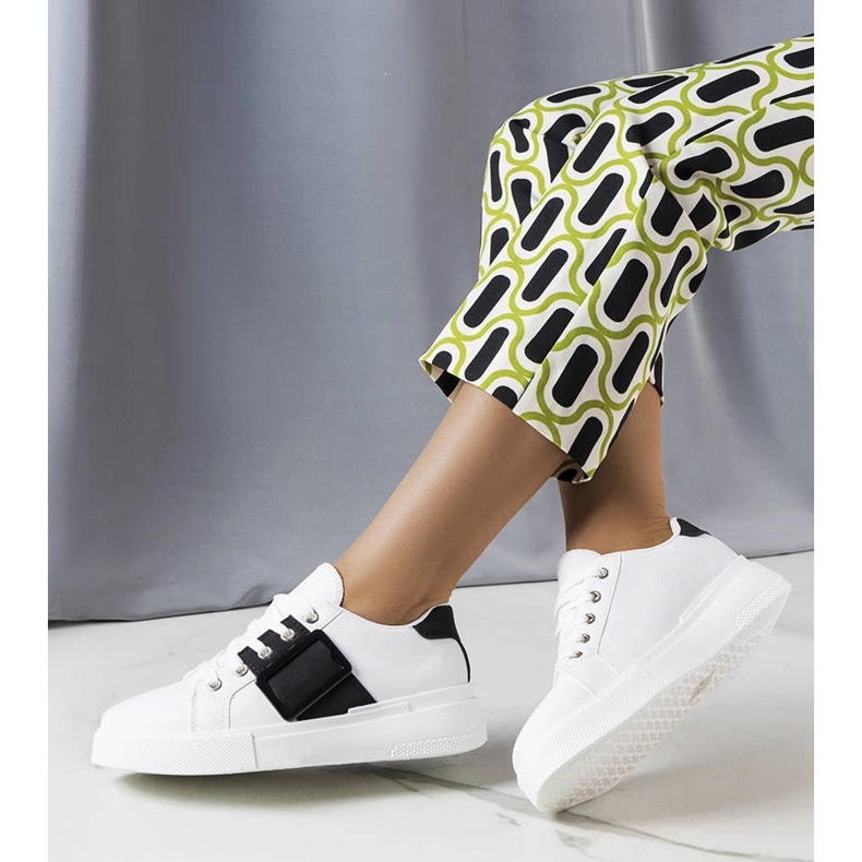 Vita sneakers dekorerade med ett svart Erin-spänne 1