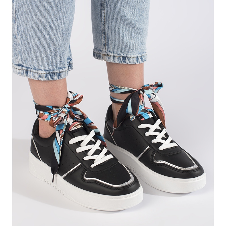 Svarta kvinnors sneakers bundna med ett band 1