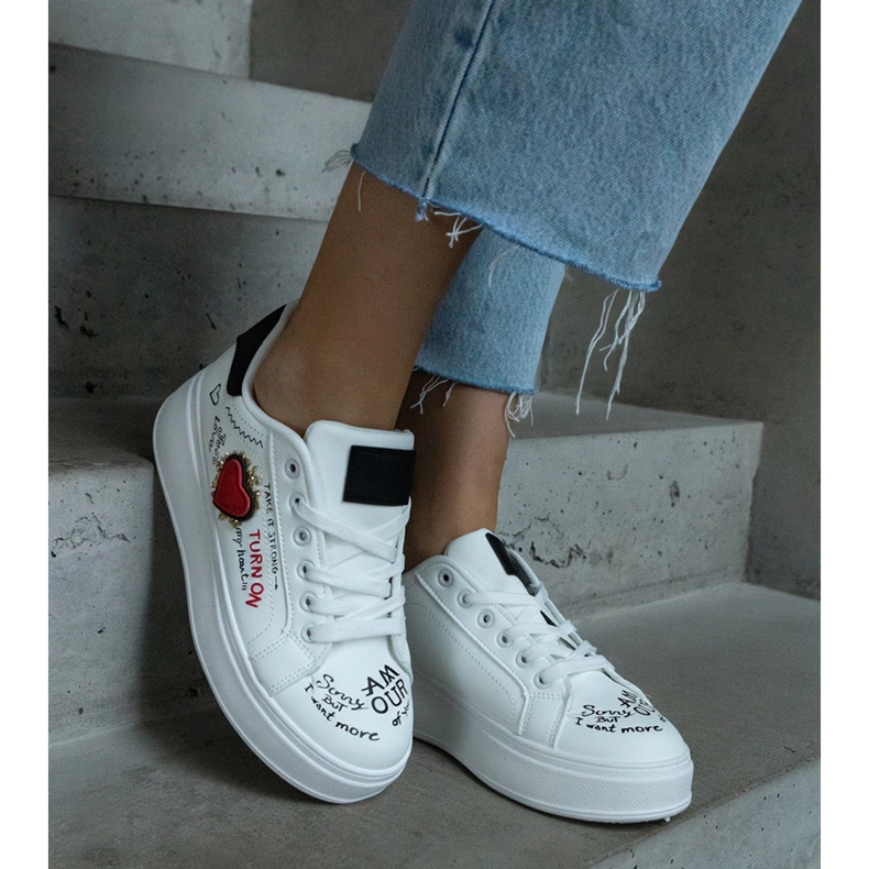 Vita sneakers dekorerade med en lapp och inskriptioner på plattformen 1