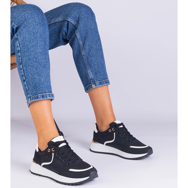 Svarta kvinnors sneakers med en gyllene införande 1