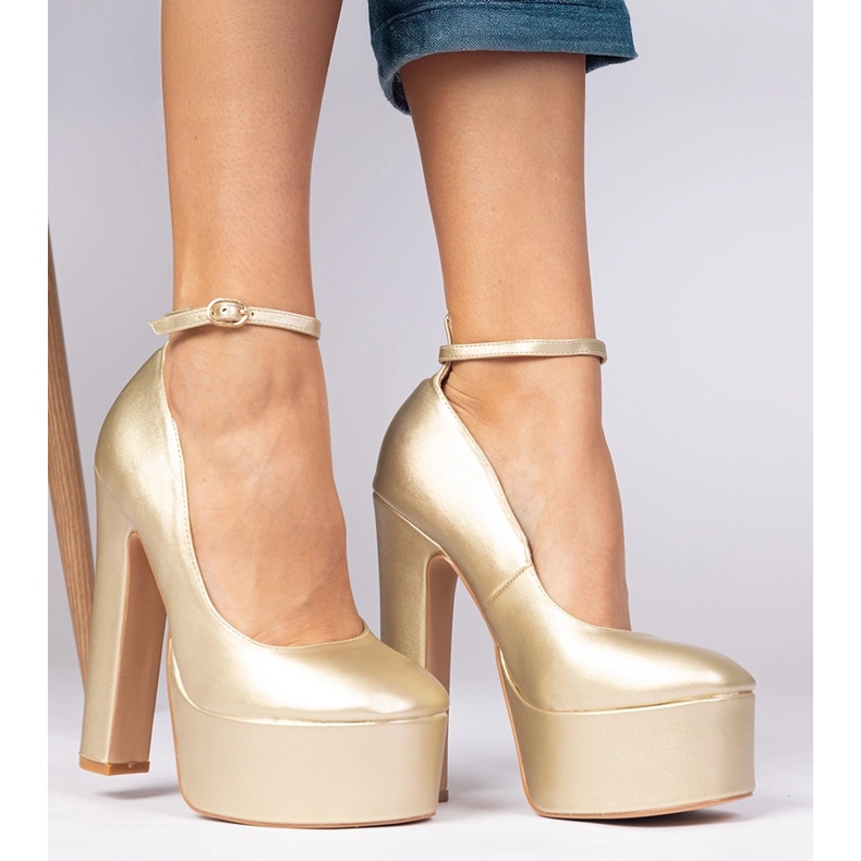 Guldmetallpumpar på en hög stolpe gyllene 2