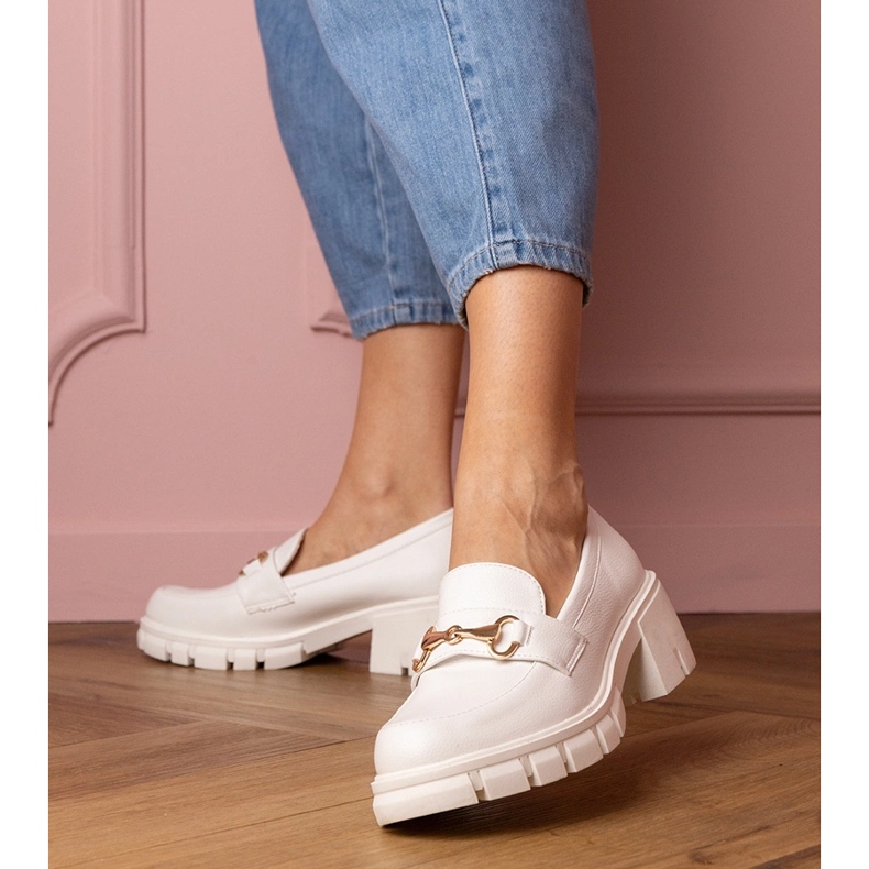 Vita skor på en låg stolpe med en gyllene prydnad 1