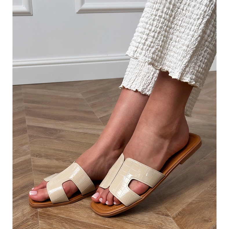 Beige klaffar på en platt sula med pressande 1