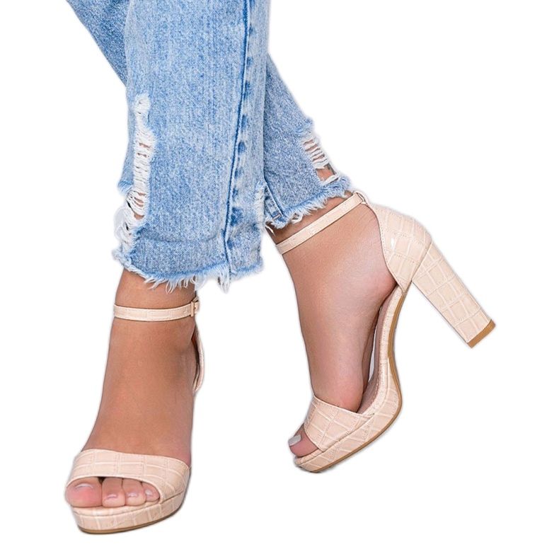 Beige sandaler på en stolpe med ett svart rosémönster 1