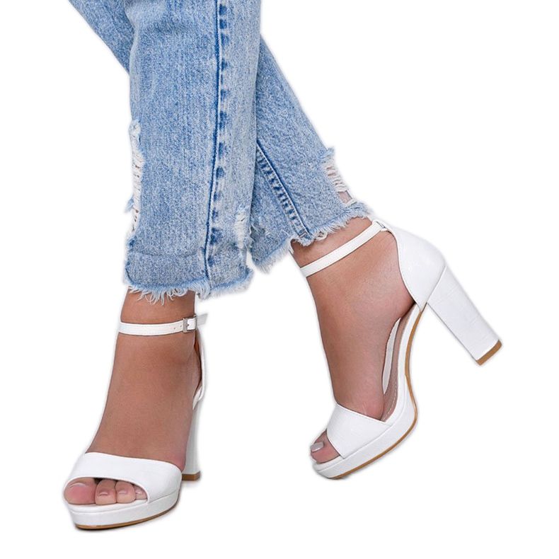 Vita sandaler på en stolpe med ett svart rosémönster 1